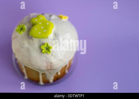 Traditional Easter kulich with white icing and light green bunny topper on soft lavender background, festive spring dessert concept Stock Photo