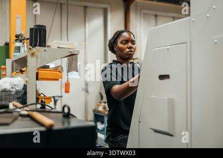 Young female worker operating machine in factory Stock Photo