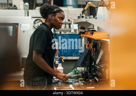 Young female worker working on manufacturing equipments while working in factory Stock Photo