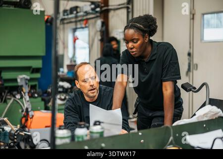 Female worker discussing instructions on paper before manufacturing products in factory Stock Photo