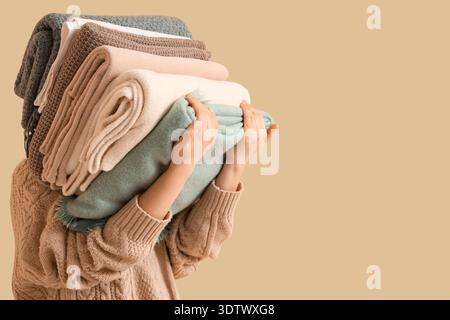 Woman with stack of plaids on beige background Stock Photo