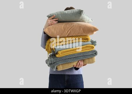 Woman with stack of plaids on light background Stock Photo