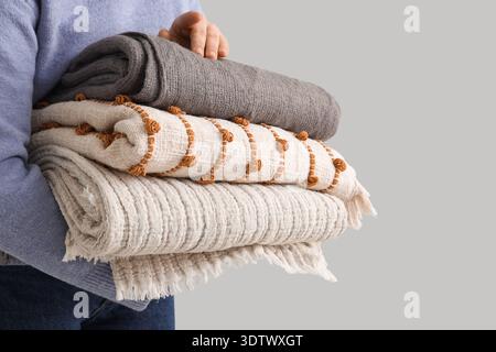 Woman with stack of plaids on light background, closeup Stock Photo