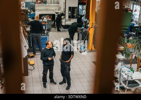 High angle view of male and female employees discussing with each other while standing in factory plant Stock Photo