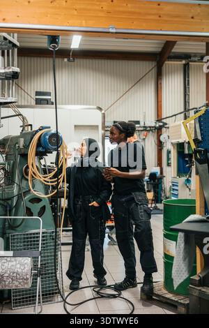 Full length of female workers operating industry machine while working in factory Stock Photo