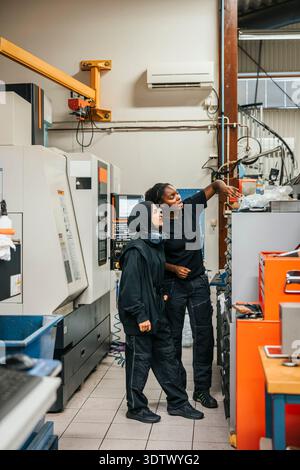 Full length of female industry workers discussing with each other while working in factory Stock Photo