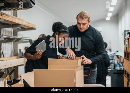 Female and male warehouse workers packing cardboard boxes for shipment Stock Photo