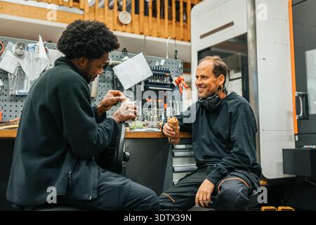 Male workers eating wrap sandwich during break in factory Stock Photo