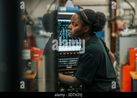 Concentrated young female metal worker operating machine in factory Stock Photo