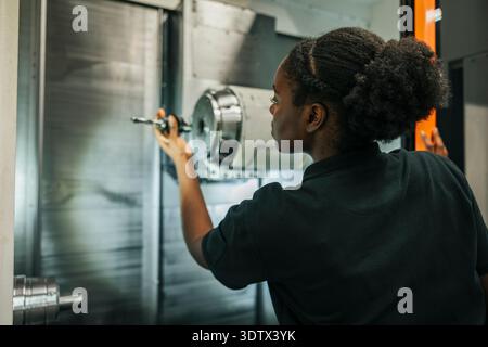 Rear view of female worker operating metal machine in industry Stock Photo