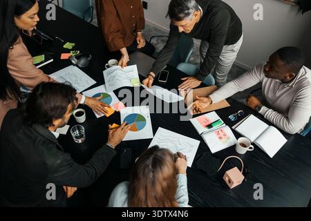 High angle view of male and female business professionals examining documents while sitting around table in office Stock Photo