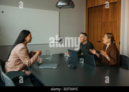 Male and female entrepreneurs communicating with client while sitting at table in office meeting room Stock Photo