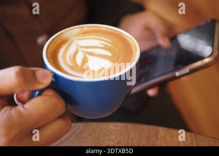 Enjoying coffee and browsing on a phone in a cafe Stock Photo