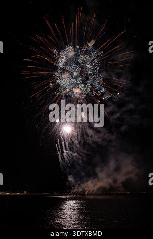 Ferragosto pyrotechnic spectacle over the sea in Grado Italy 2025: spectacular fireworks explosions at night, vibrant bursts reflecting on water. Stock Photo