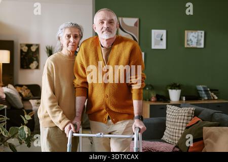 Portrait of Senior Caucasian Couple Standing Together Using Walker Indoors Stock Photo