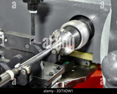 Precision valve grinding machine refacing a valve component in a mechanical workshop Stock Photo