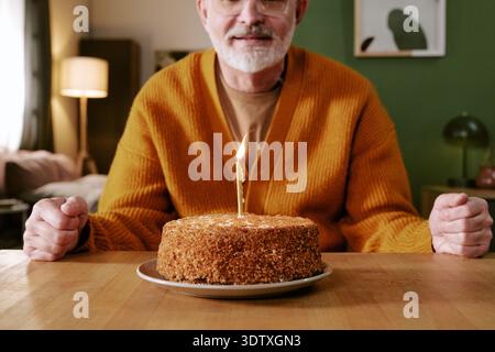 Senior Caucasian Man Smiling While Sitting with Birthday Cake on Table Stock Photo