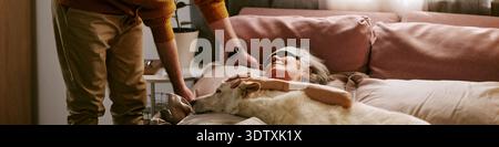 Senior Caucasian Woman Resting in Bed Petting Dog While Senior Man Visiting Stock Photo