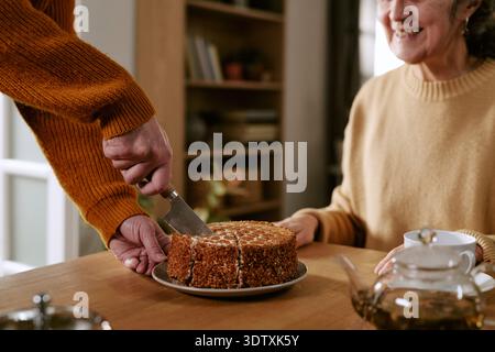 Senior Caucasian Woman Smiling While Man Slicing Cake Stock Photo