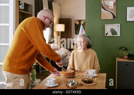 Senior Caucasian Man Serving Cake to Senior Caucasian Woman Celebrating Birthday Stock Photo