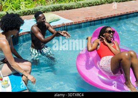Pink inflatable ring is floating in clear pool water at backyard pool near brick coping Stock Photo