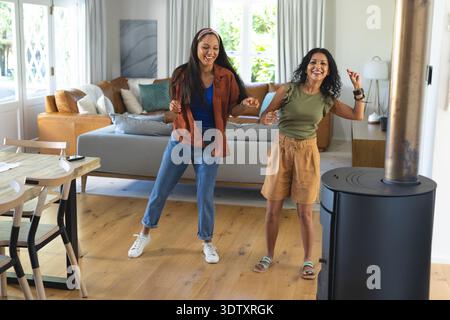 Grey sofa with pillows is sitting on wooden plank floor near wood stove and table Stock Photo