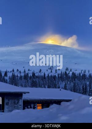 Snow sweeps over the fells in front of the moon at twilight, Hotel Pallas, Pallas-Yllaestunturi National Park, Lapland, Finland Stock Photo