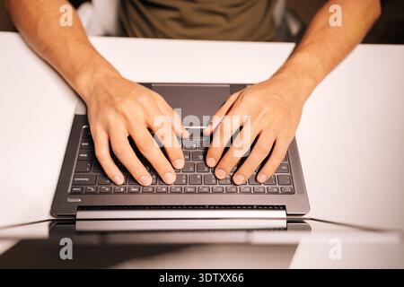 Top view of programmer hands typing on laptop keyboard, coding software, developing technology, working remotely, searching information, focusing on Stock Photo