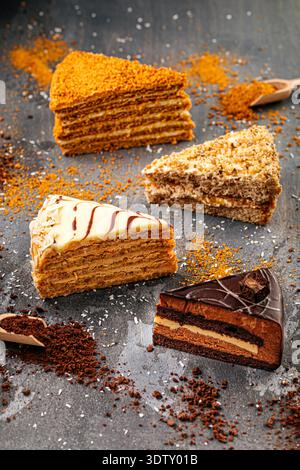Assorted layered cake slices on dark table Stock Photo