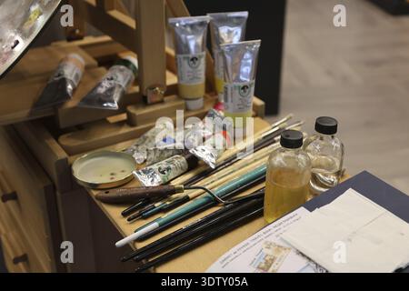 A table with various painting tools such as brushes, paints and bottles in the studio, Messe Frankfurt/M Stock Photo