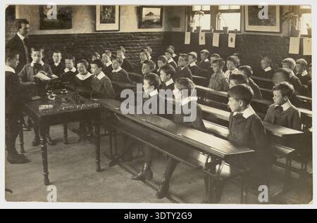 1900's Edwardian junior school boys & teacher. Victorian classroom. Learning weighing, weights & measures 1900s School children in class Circa 1905 UK Stock Photo