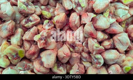A top-down, close-up view showing a large pile of fresh, raw chicken tails or parson's noses, ready for cooking or sale at a market. Stock Photo