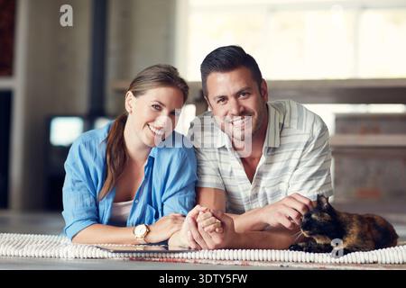 Happy couple, portrait and stroke cat in home with care, bonding and holding hands for relationship. Man, woman and smile with pet animal, connection Stock Photo