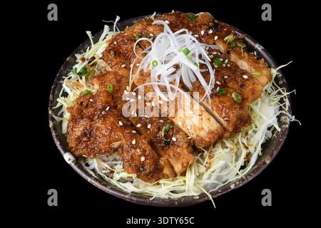 A bowl of crispy fried chicken pieces coated in savory sauce, served over steamed rice and garnished with shredded scallions. Stock Photo