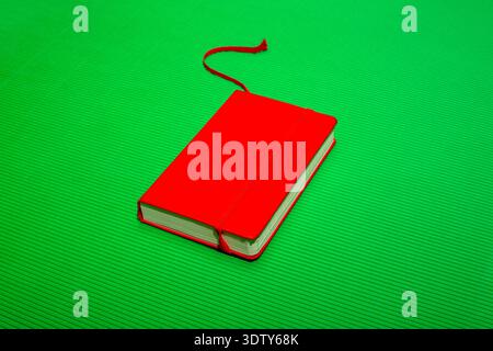 Red notebook with a bookmark on a green background Stock Photo