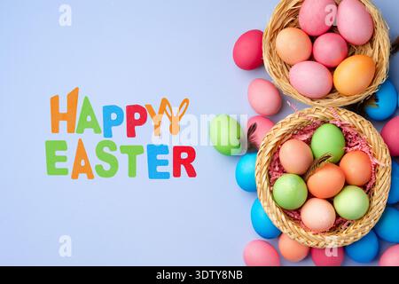 Colorful baskets with eggs and happy Easter greeting on a blue background Stock Photo
