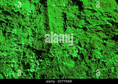 Bright green rock texture background with rough uneven surface and dark shadows. Stock Photo
