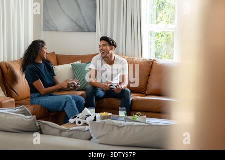 African American couple laughing and playing with controllers and white VR headset in living room Stock Photo
