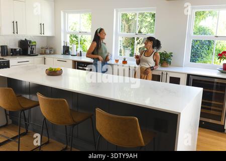 White marble island is anchoring modern kitchen with leather bar stools and citrus bowl Stock Photo