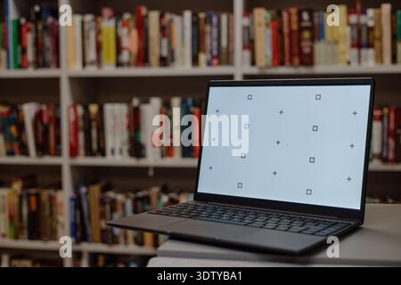 Laptop Displaying Blank Screen in Library Environment Stock Photo