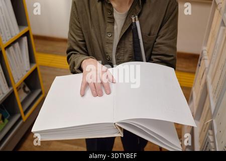 Middle Aged Man Reading Braille Book in Library While Standing Stock Photo