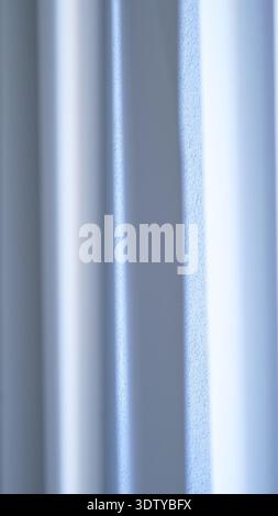 Textured white wall with vertical lines and soft light reflections creating a subtle pattern Stock Photo