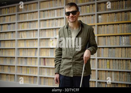 Portrait of Young Adult Man Using Cane Navigating Library Stock Photo