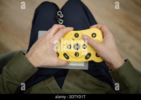 Blind Man Using Adaptive Electronic Controller While Sitting in Library Stock Photo