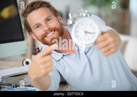 young male contractor repairing alarm clock at workshop Stock Photo