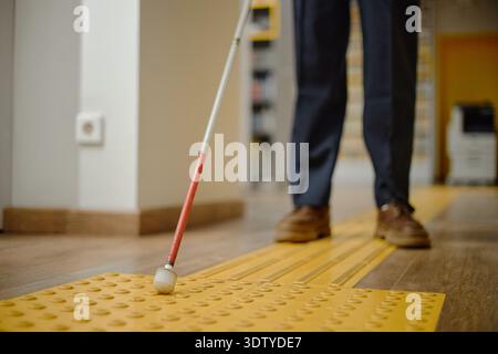Man Navigating Library with Cane Using Tactile Path Stock Photo
