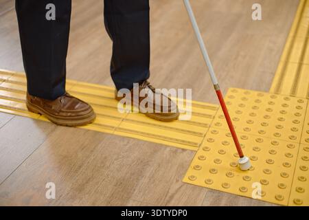 Middle Aged Man Navigating Library Floor Using Cane for Blind Stock Photo