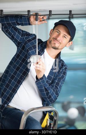 young guy repairs a light ceiling Stock Photo
