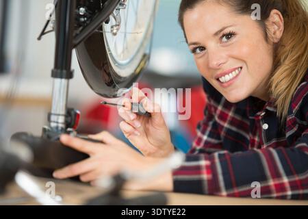happy young woman fixing her bicycle Stock Photo
