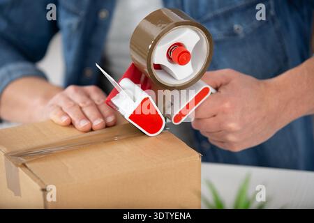 a guy hands sealing cardboard boxes with duct tape Stock Photo